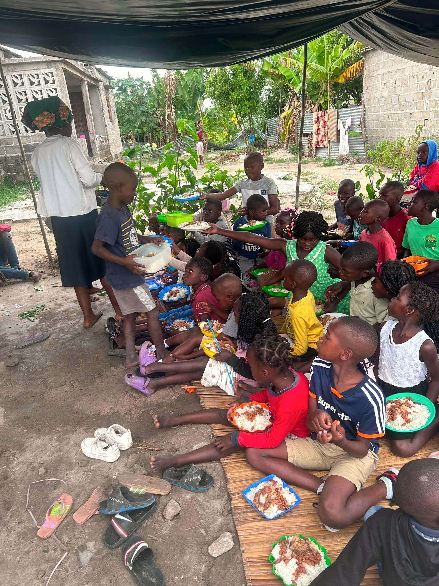 Em Dondo, no projeto alimento, uma irmã passa um prato de comida a uma criança